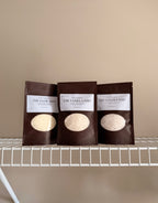 Three laundry scent booster packages in The Vanilla Edit, The Golden Edit, and The glow Edit. On a beige background with a white shelf.