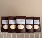Five sampler pouches on a beige background with a white shelf