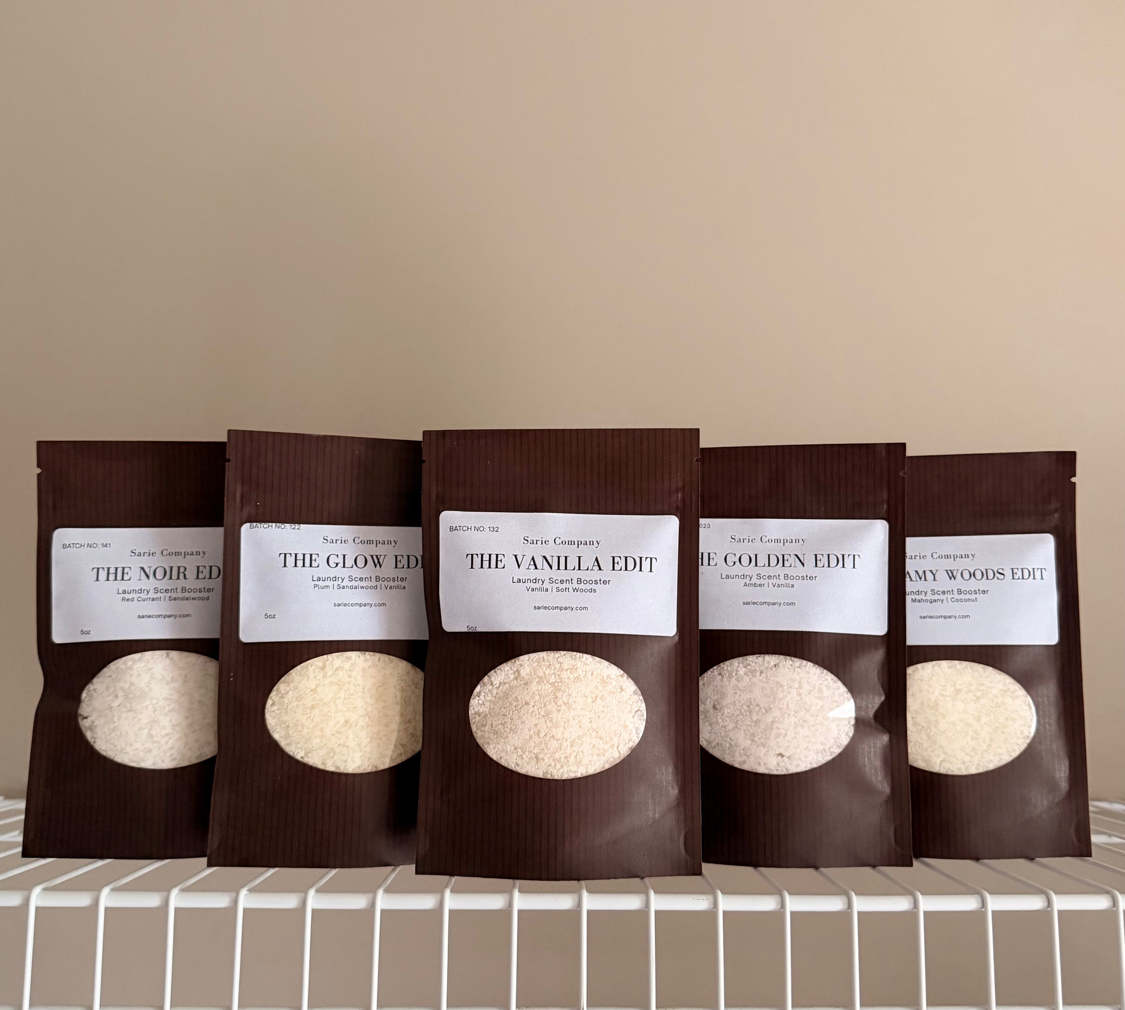 Five sampler pouches on a beige background with a white shelf