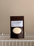 The Glow Edit Sample size pouch on a beige background with a white shelf