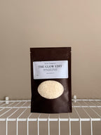 The Glow Edit Sample size pouch on a beige background with a white shelf