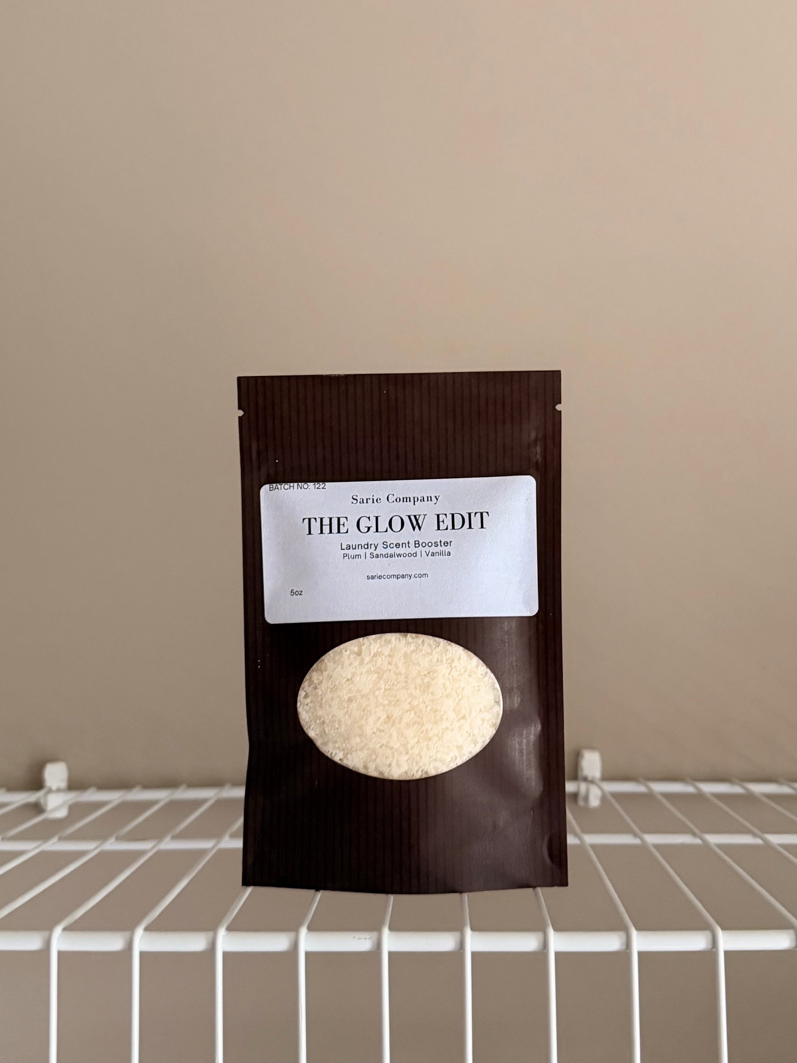 The Glow Edit Sample size pouch on a beige background with a white shelf