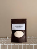 The Noir Edit sampler pouch on a beige background with a white shelf.