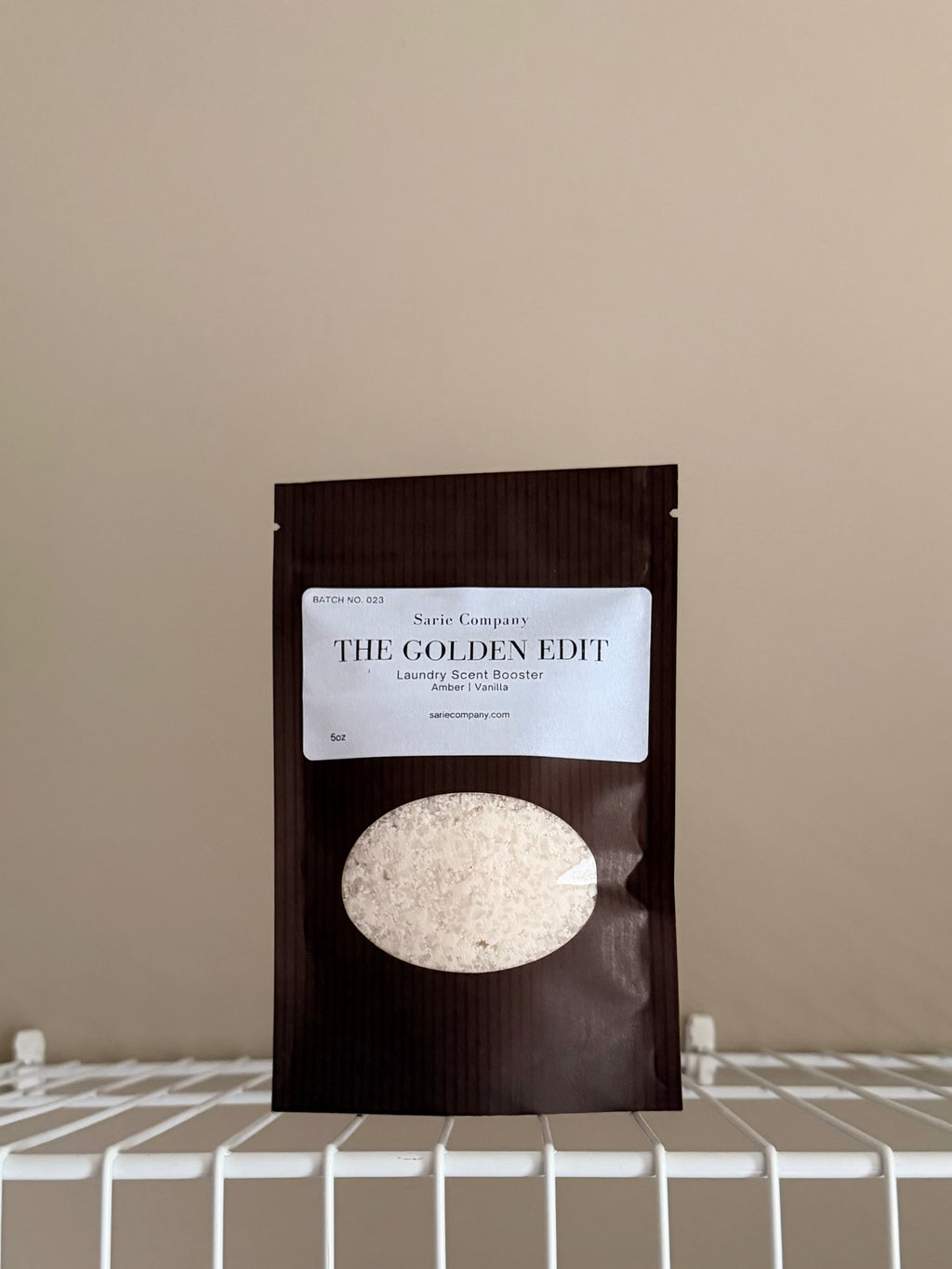 The Golden Edit sample size pouch on a beige background with a white shelf