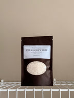 The Golden Edit sample size pouch on a beige background with a white shelf