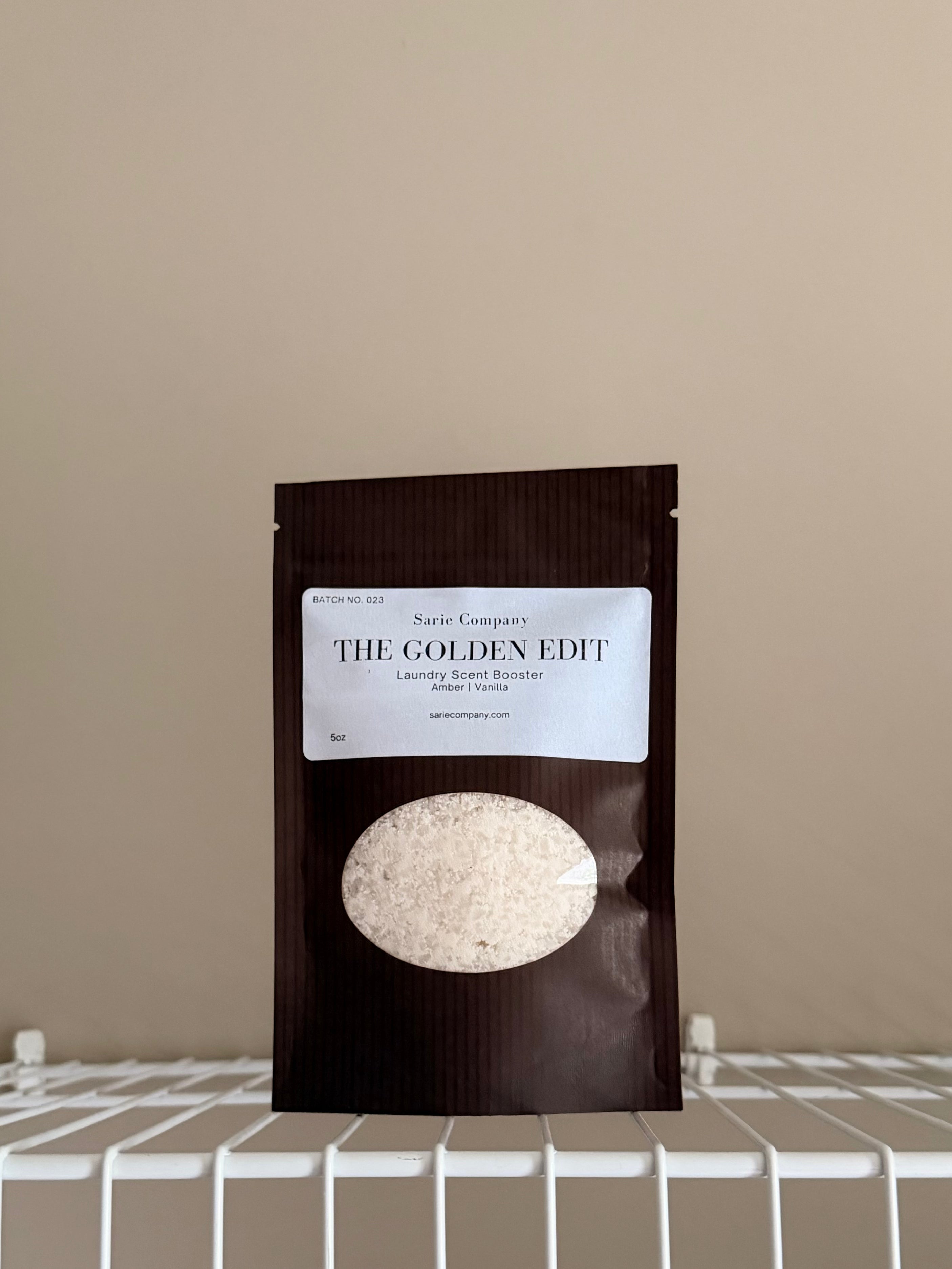 The Golden Edit sample size pouch on a beige background with a white shelf