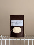 The Creamy Woods Edit sampler pouch on a beige background with a white shelf.