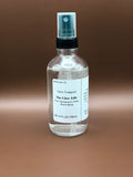 Clear glass spray bottle with a label on a brown background