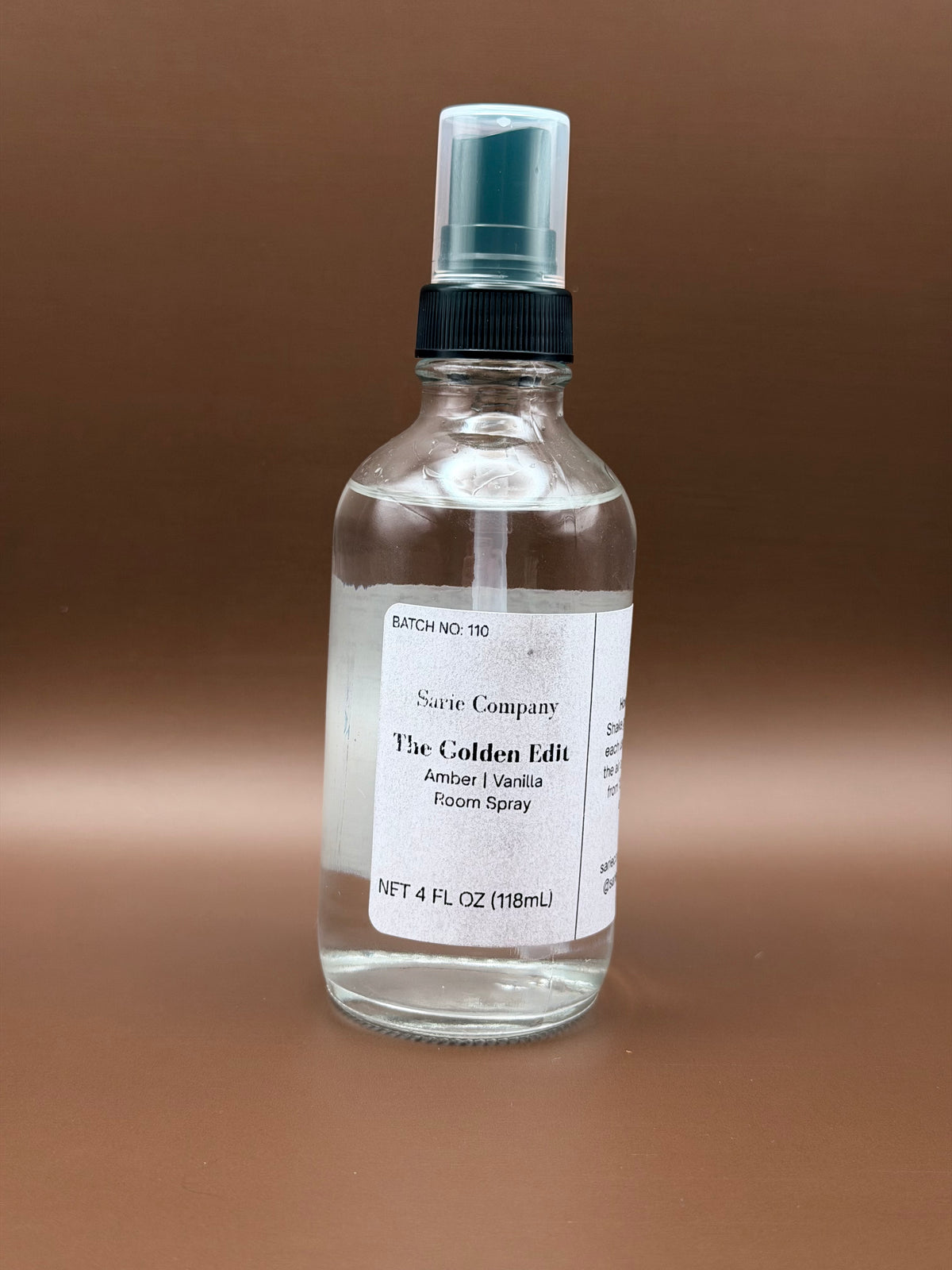 Clear spray bottle with a label on a brown background