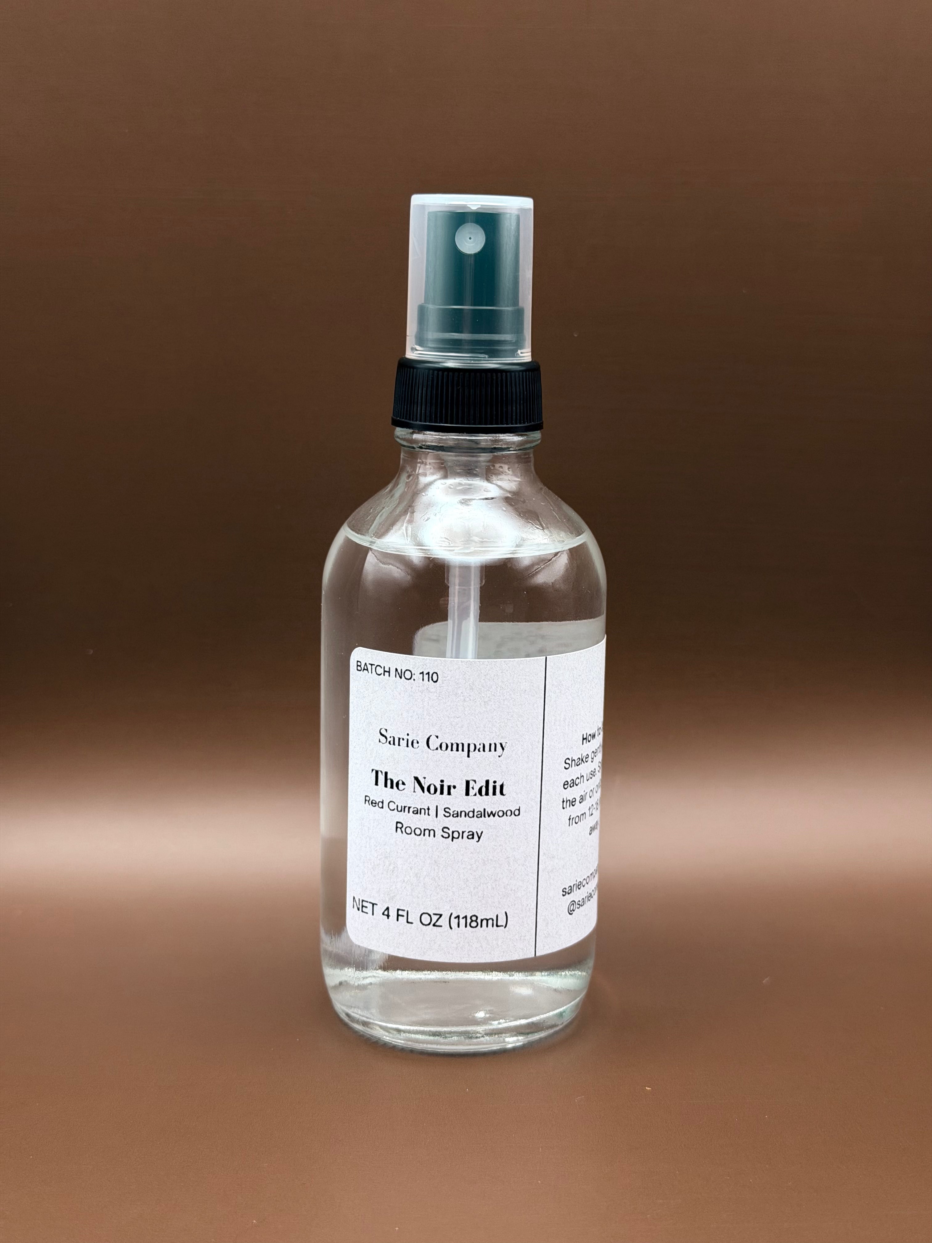 Clear spray bottle with a label on a brown background